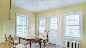 A room with a round wooden table, two chairs, a white radiator, and three windows with white frames. - Private bathroom with Large Balcony in Montréal close St. Lawrence River (Montréal)