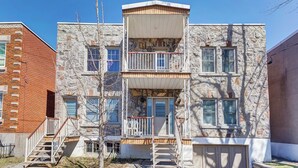 A multi-story building with a stone facade, multiple balconies, and a small porch area. - Private bathroom with Large Balcony in Montréal close St. Lawrence River (Montréal)
