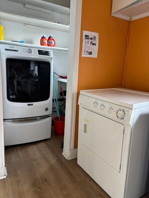 A laundry room with a front-loading washer and dryer, a microwave, and two bottles of detergent on the shelf. - Private bathroom with Large Balcony in Montréal close St. Lawrence River (Montréal)