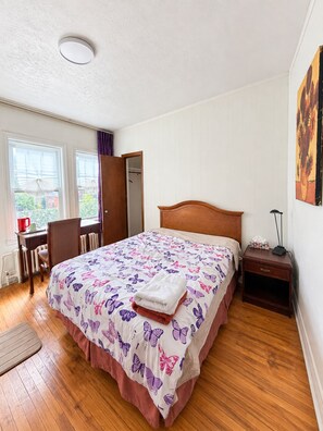 A bedroom with a wooden bed, a desk with a chair, a radiator, and a window with curtains. - Private bathroom with Large Balcony in Montréal close St. Lawrence River (Montréal)