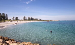 A beach with clear water, a sandy shore, and a building in the background. - Wray House – Spacious Modern Fremantle Stay (Fremantle)