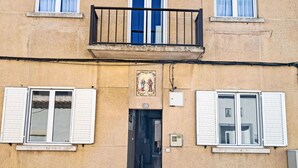 Ein Gebäude mit Balkon, zwei Fensterläden, einer Tür und einem kleinen Schild darüber.