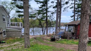 A lakeside property with a dock, a red cabin, and a grassy area with trees.