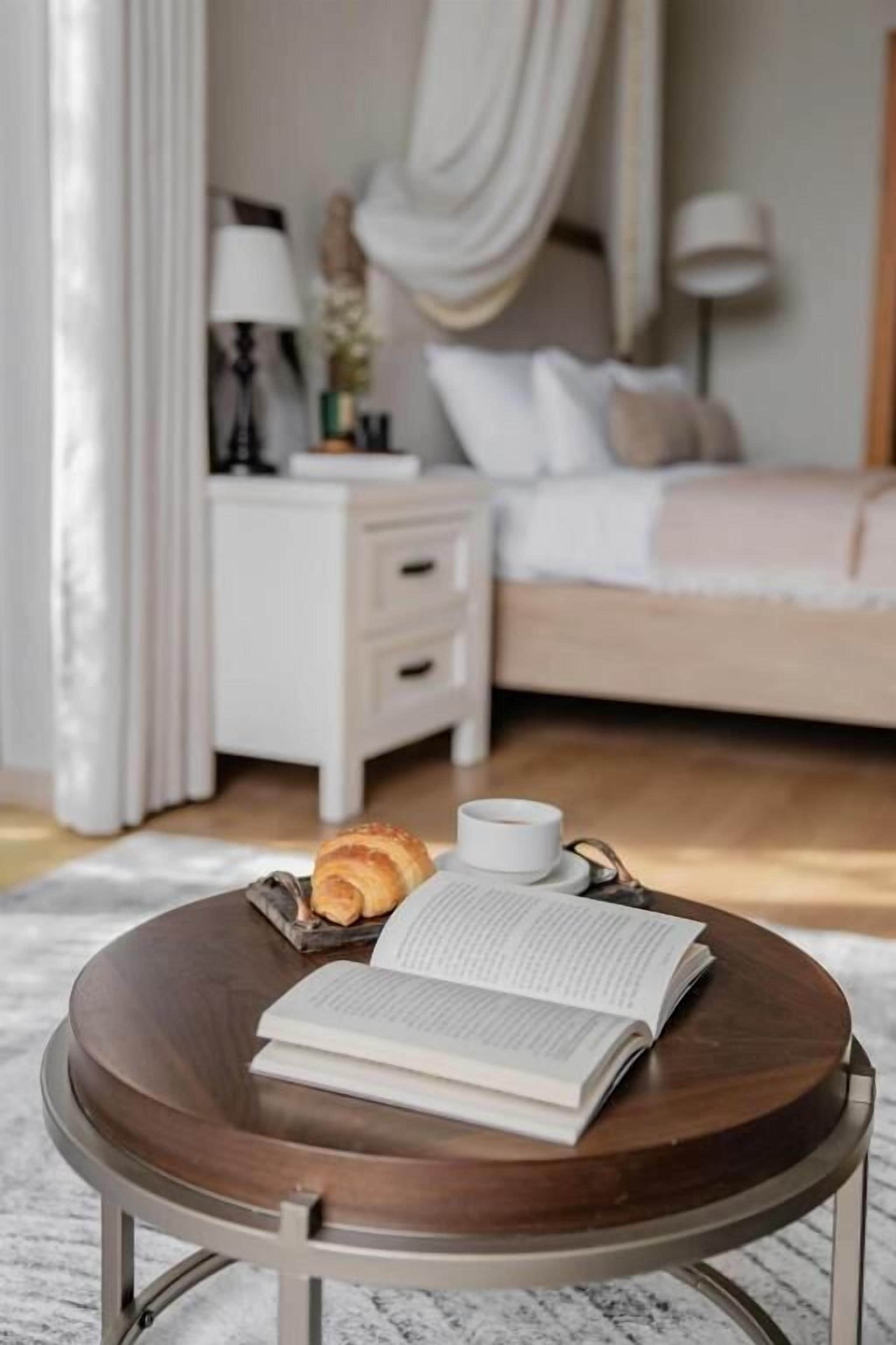 Una camera da letto con un letto, un comodino con una lampada e una finestra con tende.