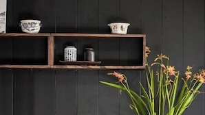 A kitchen with wooden cabinets, a black wall, and a shelf with decorative items.