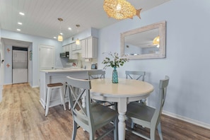 A dining area with a round table, chairs, a vase, and a mirror on the wall. - Beachfront 2BR Condo with Pool and Beach Access (Gulf Shores)