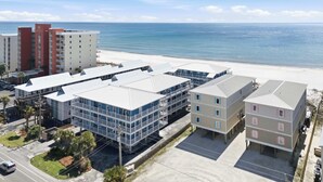 A coastal hotel complex with multiple buildings, a parking area, and a beach view. - Beachfront 2BR Condo with Pool and Beach Access (Gulf Shores)