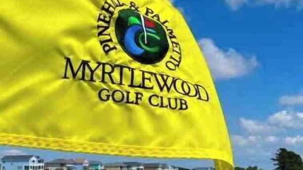 Un drapeau arborant l’inscription « Myrtlewood Golf Club » et un logo, le tout sur fond de ciel bleu.