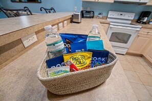 A kitchen counter with a woven basket containing bottled water, a book, and food items. - Ground Floor 2BR Near Golf & Beach (Myrtle Beach)