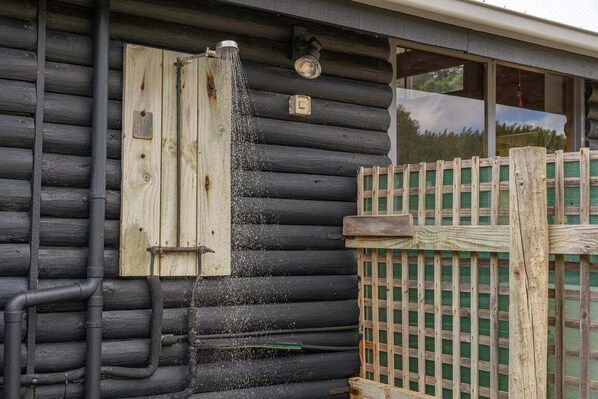 A log cabin with a wooden door, a window, and a wooden fence.