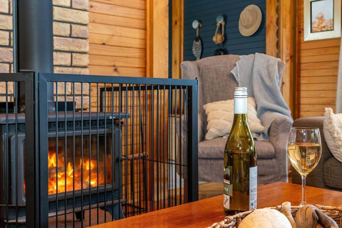 A cozy room with a fireplace, a bottle of wine, and a glass on a wooden table.