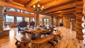 A wooden cabin interior with a large dining table, benches, and a chandelier. - New Cabin! Family Fun - 6 BR - Smoky Mountains Views, Hot Tub, Arcades (Gatlinburg)
