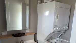 A compact bathroom with a sink, mirror, and a white washing machine.