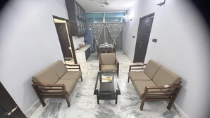 A living room with a sofa set, a coffee table, and a dining area with a table and chairs. - Modern 2BR in Elite DOHS Baridhara – Secure, Quiet & Stylish (Dhaka)