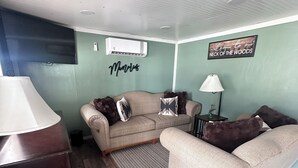 A living room with a sofa, a coffee table, a lamp, and a TV. - Peaceful 2-bedroom cabin with AC in charming Delbarton (Delbarton)