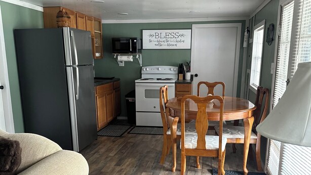 A compact kitchen with a refrigerator, microwave, stove, and dining table with chairs. - Peaceful 2-bedroom cabin with AC in charming Delbarton (Delbarton)
