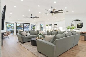 Ein modernes Wohnzimmer mit einem Ecksofa, einem Couchtisch und Deckenventilatoren.