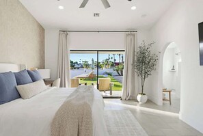 Ein modernes Hotelzimmer mit einem großen Bett, Blick auf den Außenpool und einer Zimmerpflanze.