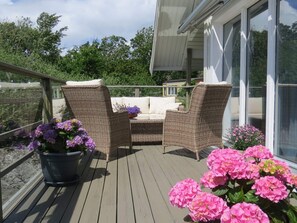Eine Holzterrasse mit Korbmöbeln und Blumentöpfen.