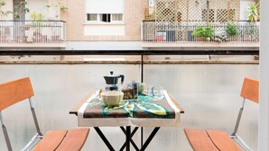 A balcony with a table set for two, a pot, and a bowl.