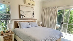 A bedroom with a bed, nightstands, a lamp, a painting, and a view through the window. - Tranquility on Buderim - large, light family home with expansive views. (Buderim)