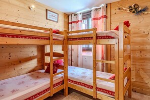 Ein Schlafraum mit Etagenbetten, Holzwänden und einem gerahmten Bild an der Wand.