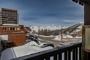 Ett hotell med utsikt över snöklädda berg, en parkeringsplats och en väg med en rondell.