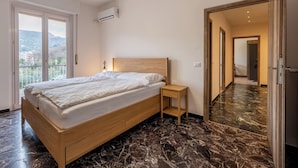 Un dormitorio con cama, mesita de noche y vistas a la ciudad a través de amplios ventanales.