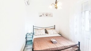 A bedroom with a metal bed frame, a bedside table with a lamp, a hanging light fixture, and a window with sheer curtains. - Terrazza Silvi Marina by Interhome (Silvi Marina)