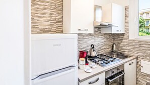 A modern kitchen with a white refrigerator, a gas stove, and a window with a view of buildings. - Terrazza Silvi Marina by Interhome (Silvi Marina)