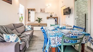 A modern living room with a sofa, dining table, chairs, and a TV mounted on the wall. - Terrazza Silvi Marina by Interhome (Silvi Marina)