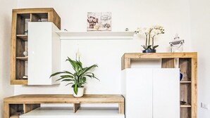 A modern living room with a white sofa, wooden shelves, a potted plant, and a decorative piece on the wall. - Terrazza Silvi Marina by Interhome (Silvi Marina)