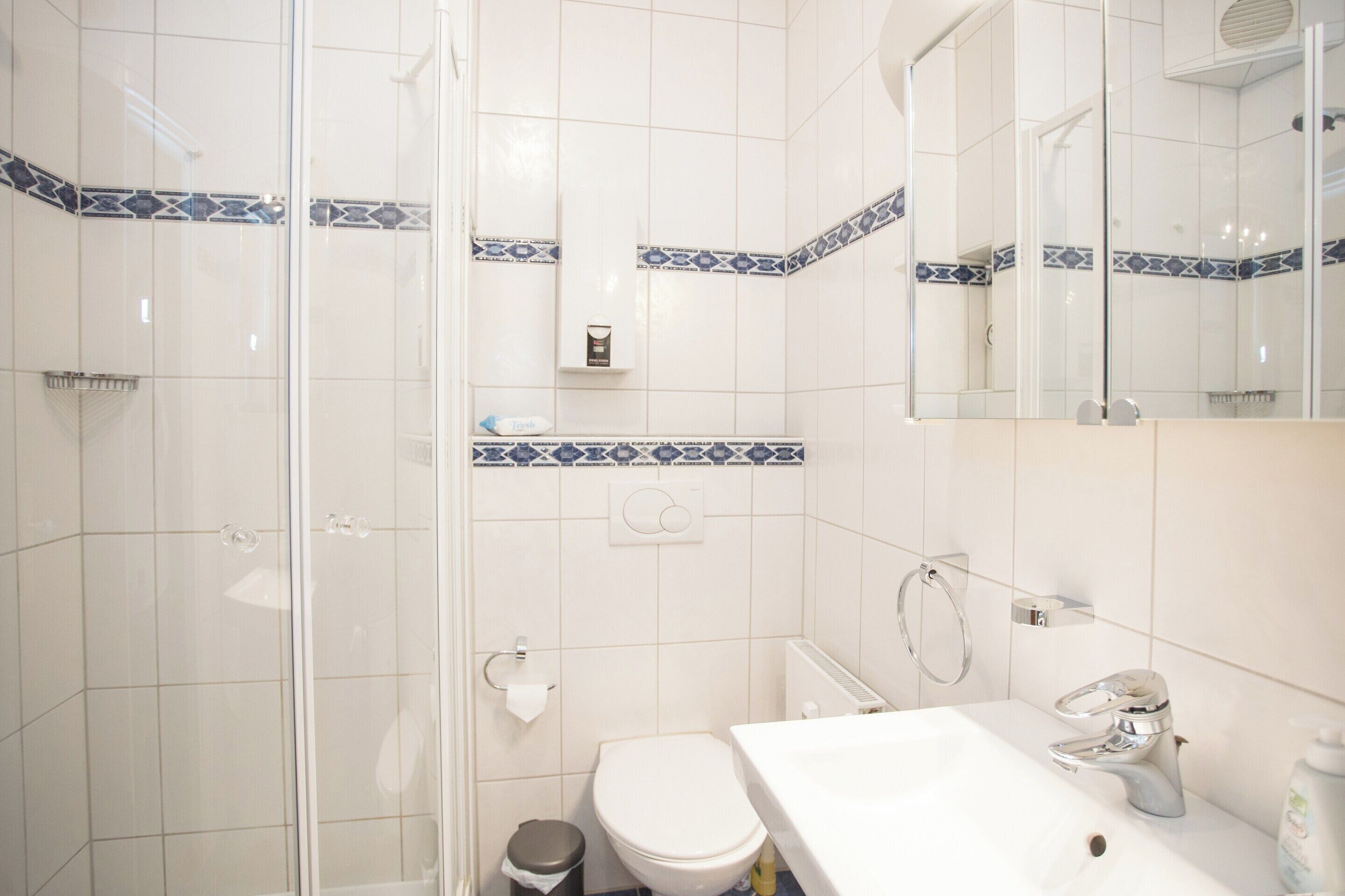 Un baño con ducha, inodoro, lavamanos y espejo.