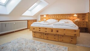 Een slaapkamer met schuine plafonds, dakramen, een houten bed, nachtlampen en een radiator.