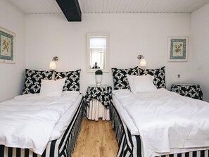 A double room with two beds, a small table, a mirror, and framed pictures on the walls.