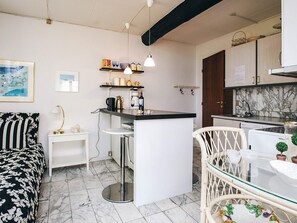 A compact kitchen with a central island, white cabinetry, and a marble backsplash.