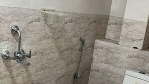 A bathroom with a shower, toilet, and a white bucket.