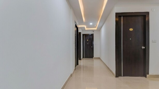 A hallway with a polished floor, dark wooden doors, and recessed lighting.