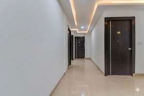 A hallway with a polished floor, dark wooden doors, and recessed lighting. - Hotel Sai Crystal (Bengaluru)