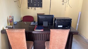 A conference room with a dark wooden table, two HP desktop computers, a red office chair, and a black chair.
