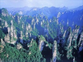 A mountainous landscape with dense green forests and rocky cliffs.