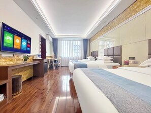 A modern hotel room with a large flat-screen TV, a desk with a chair, a bed with two pillows, and a large mirror.