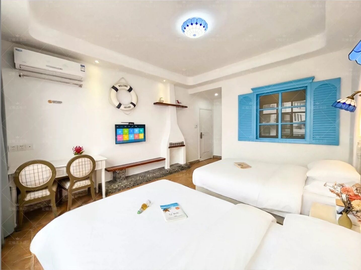 A hotel room with two beds, a TV, a small table, and a chair.