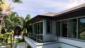 A modern two-story building with large windows, a balcony, and a well-maintained garden. - 3-bedroom Pool Villa in lovely Tambon Kamala with cool AC (Tambon Kamala)