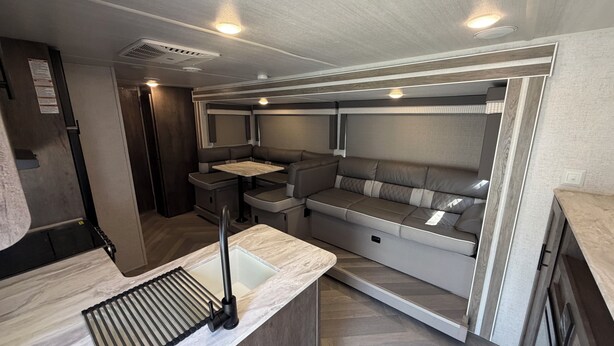A compact RV interior with a kitchenette, seating area, and a small table. - Family Friendly Bunkhouse RV (Jasper)