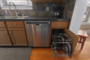 A modern kitchen with a dishwasher, built-in oven, and a dish rack. - Comfortable Cozy Home,30 Day Stays_Sleeps8 (Kansas City)