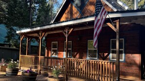 Une cabane rustique dotée d’une véranda, de balustrades en bois et d’un drapeau.
