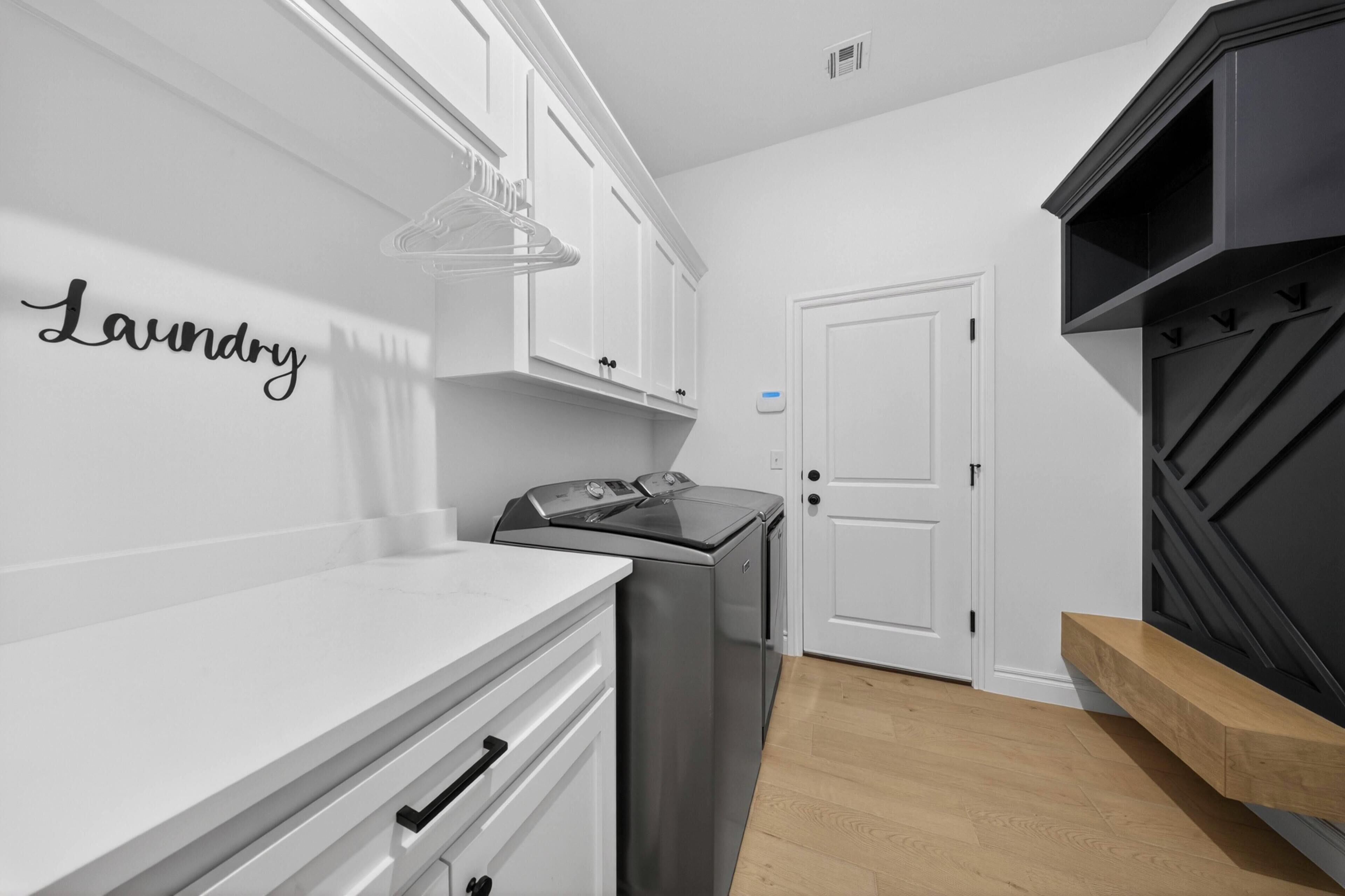 A modern kitchen with white cabinetry, a stainless steel washer, a built-in oven, and a black accent wall.
