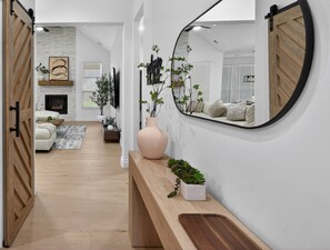 A modern living room with a fireplace, a large mirror, and a wooden bench. - The Soft Modern House - Designer Home + Cozy Vibes (Oklahoma City)