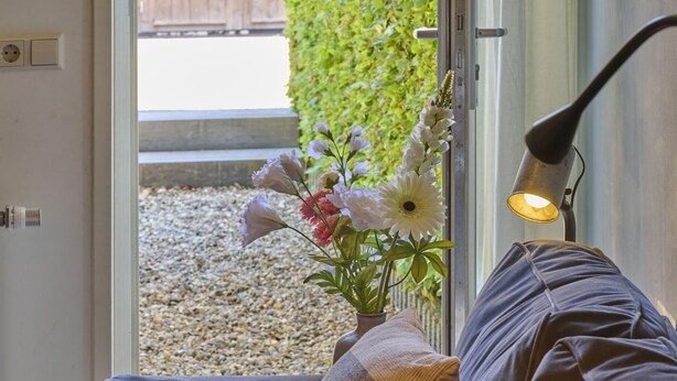 Una habitación con sofá, lámpara y ventana con vistas a un jardín.